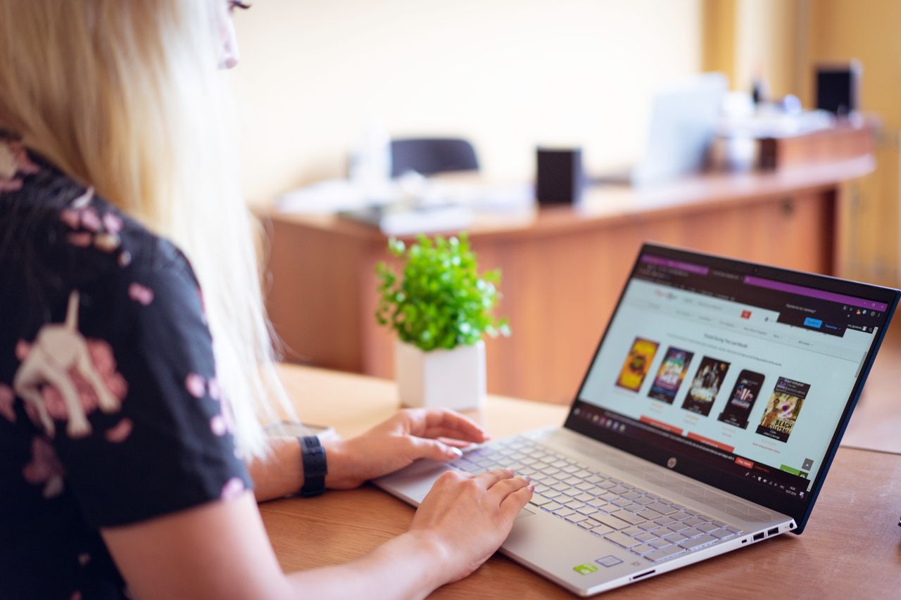 A woman browsing an online store on a laptop in a modern home office setting.